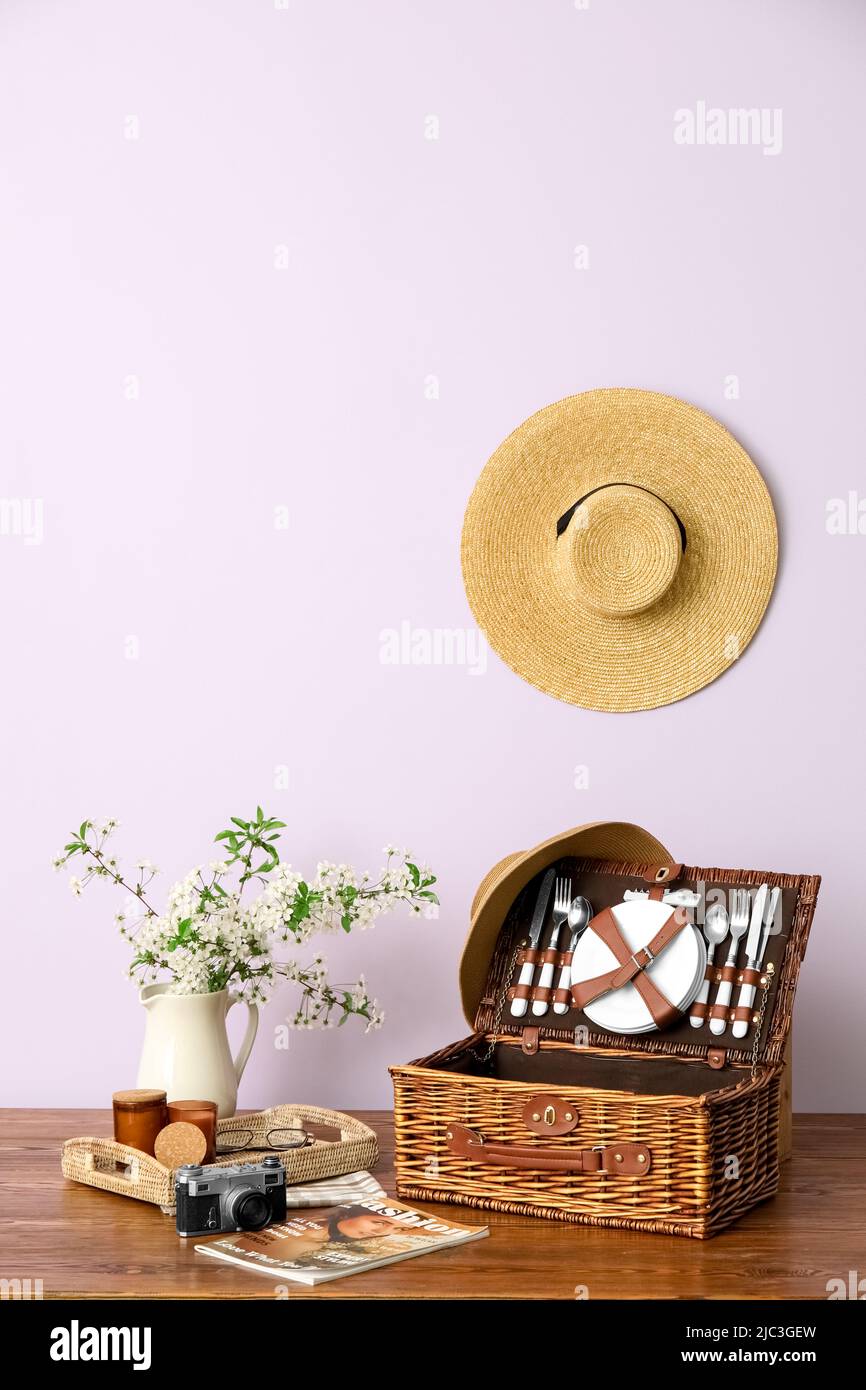 Cestino con stoviglie, macchina fotografica, rivista e rami fioriti in vaso  sul tavolo vicino alla parete della luce Foto stock - Alamy