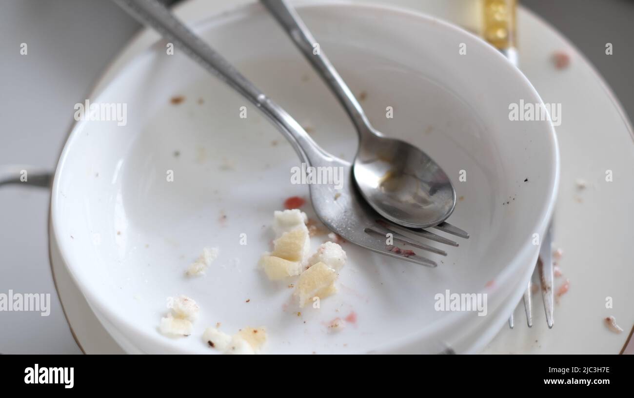 Piatti sporchi primo piano, cucchiaio, forchetta, piatti con gli avanzi di cibo impilati nel lavandino. Foto Stock