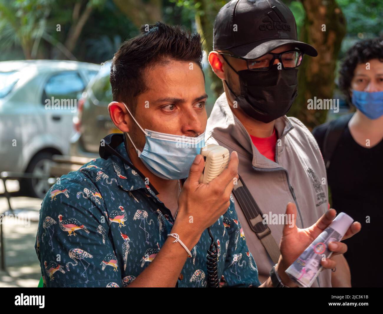 Medellin, Antioquia, Colombia - Febbraio 19 2022: Giovane uomo sudamericano con camicia blu e maschera facciale guarda i colloqui in un microfono Foto Stock