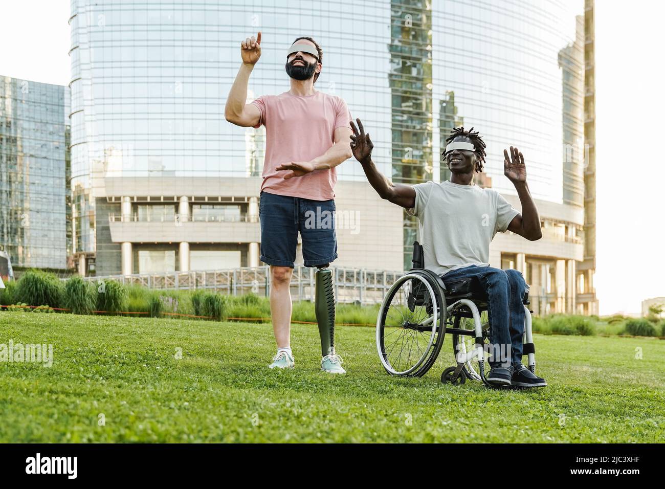Amici multirazziali con disabilità utilizzando occhiali futuristici realtà aumentata all'aperto a Park City - Focus su uomo africano seduto su sedia a rotelle Foto Stock