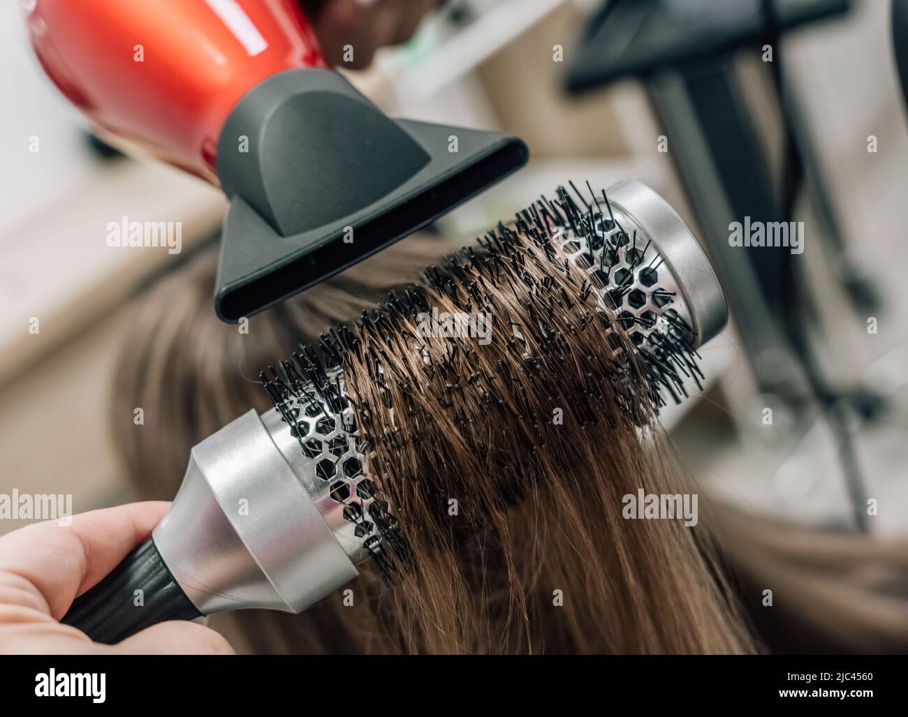 Asciugando i capelli biondi con un asciugacapelli e una spazzola rotonda. Foto di alta qualità Foto Stock