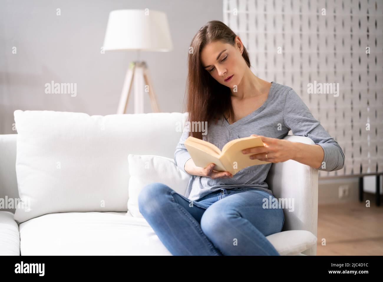 Persona adulta seduta sul libro lettura divano. Stile di vita di rilassamento Foto Stock