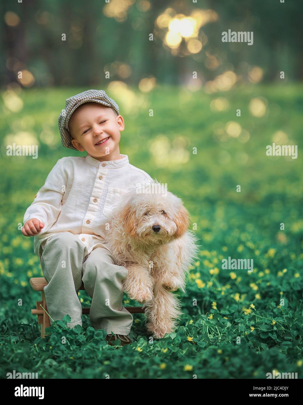 Il ragazzino e il suo cane si stoppano insieme sull'erba. Bambino felice abbracciando il suo animale sorridendo con gli occhi chiusi. Foto Stock