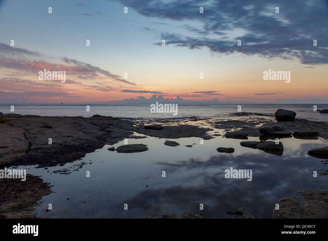 Massi e rocce nel surf sulla costa del Mar Baltico al tramonto, lunga esposizione Foto Stock