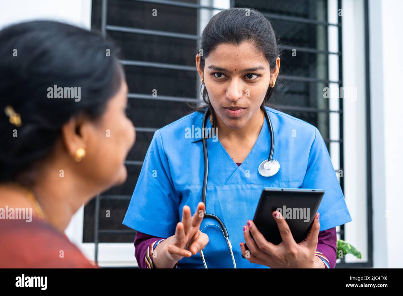 Il medico o l'infermiere consigliano la donna di mezza età vedendo il rapporto dal tablet digitale nella casa di cura - il consiglio di tecnologia, di sanità e di servizio medico Foto Stock