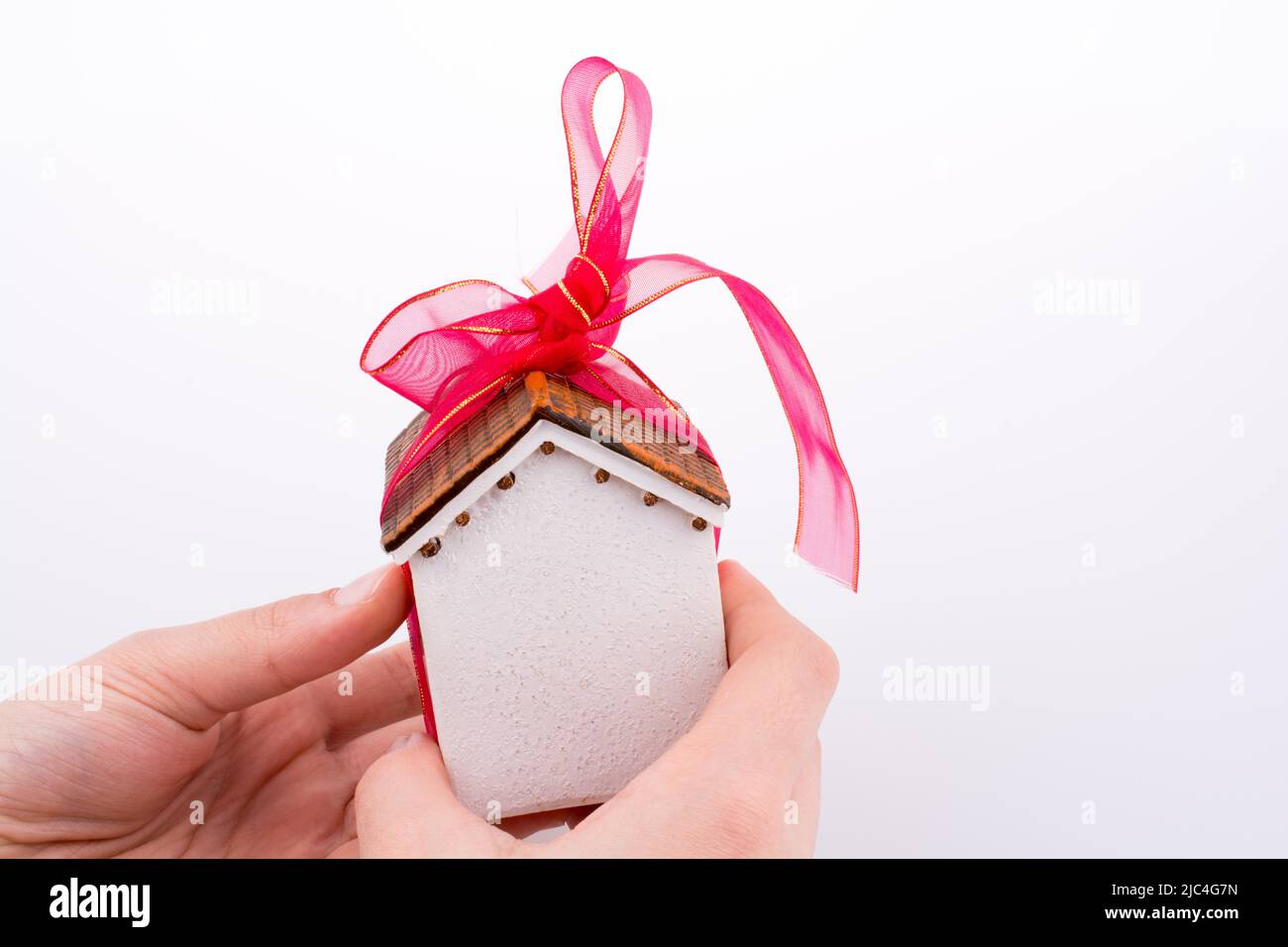 Mano che regge un modello di una casa con un nastro rosa Foto Stock