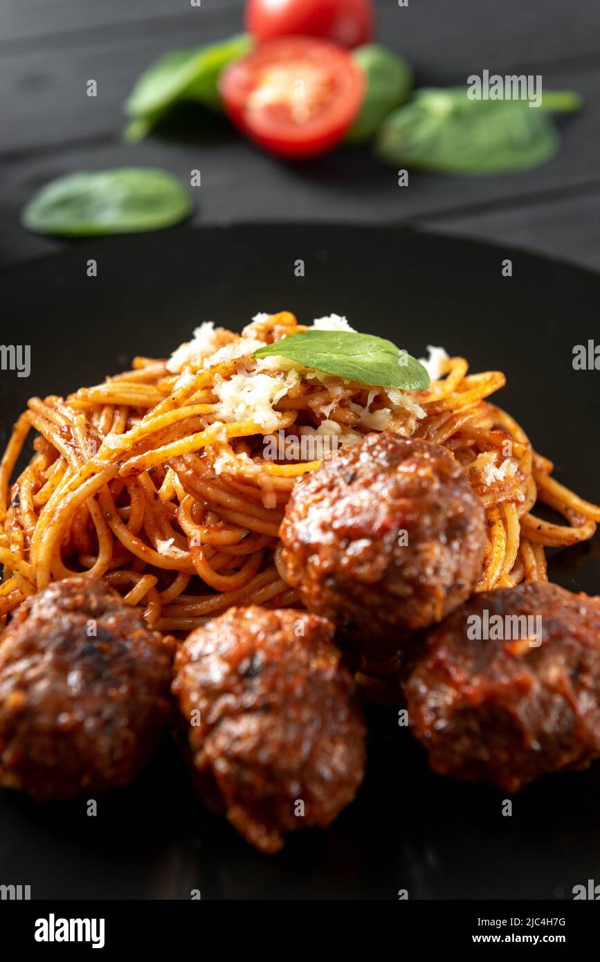 Polpette di carne con salsa di pomodoro e pasta sul piatto scuro. Scatto verticale. Foto Stock