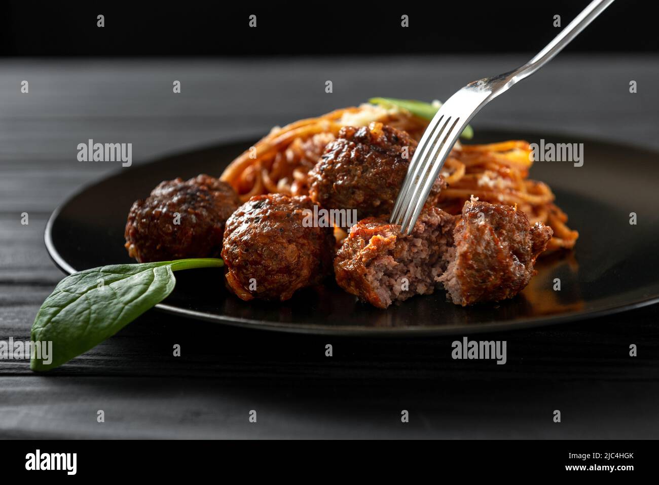 Pasta italiana con polpette di carne e salsa di pomodoro e basilico. Una forcella infila la sfera di carne Foto Stock