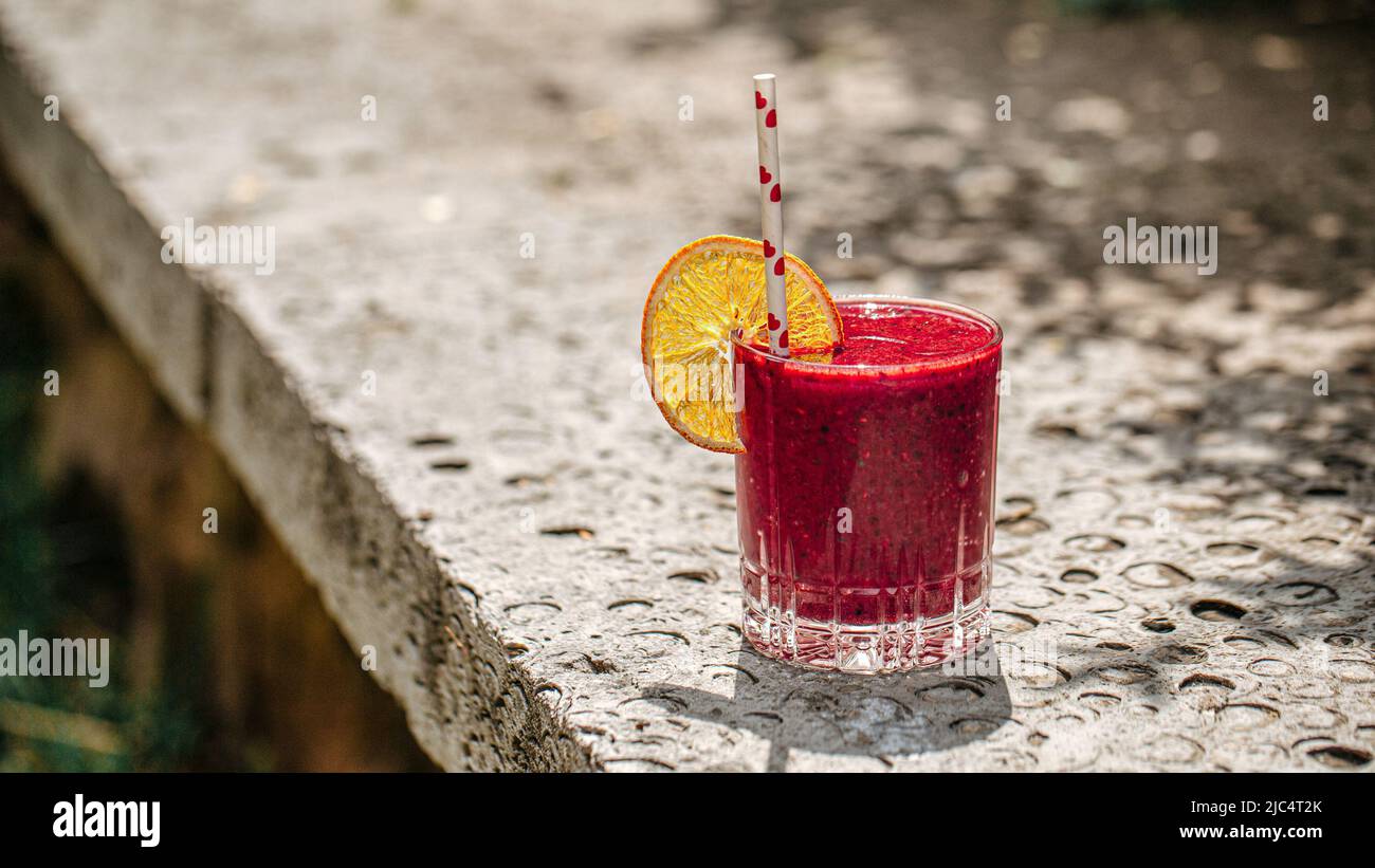 Bicchiere di frullato fresco alla bacche con fetta d'arancia Foto Stock