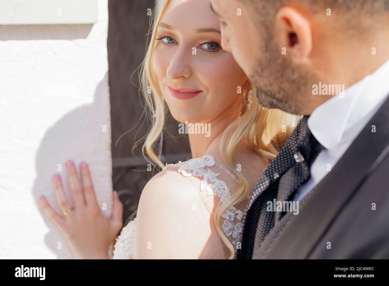 Ritratto di giovane sposa bionda in abito bianco e brunet sposo in abito sorridente e a piedi sulla strada della città in Italia primo piano, sfondo urbano Foto Stock
