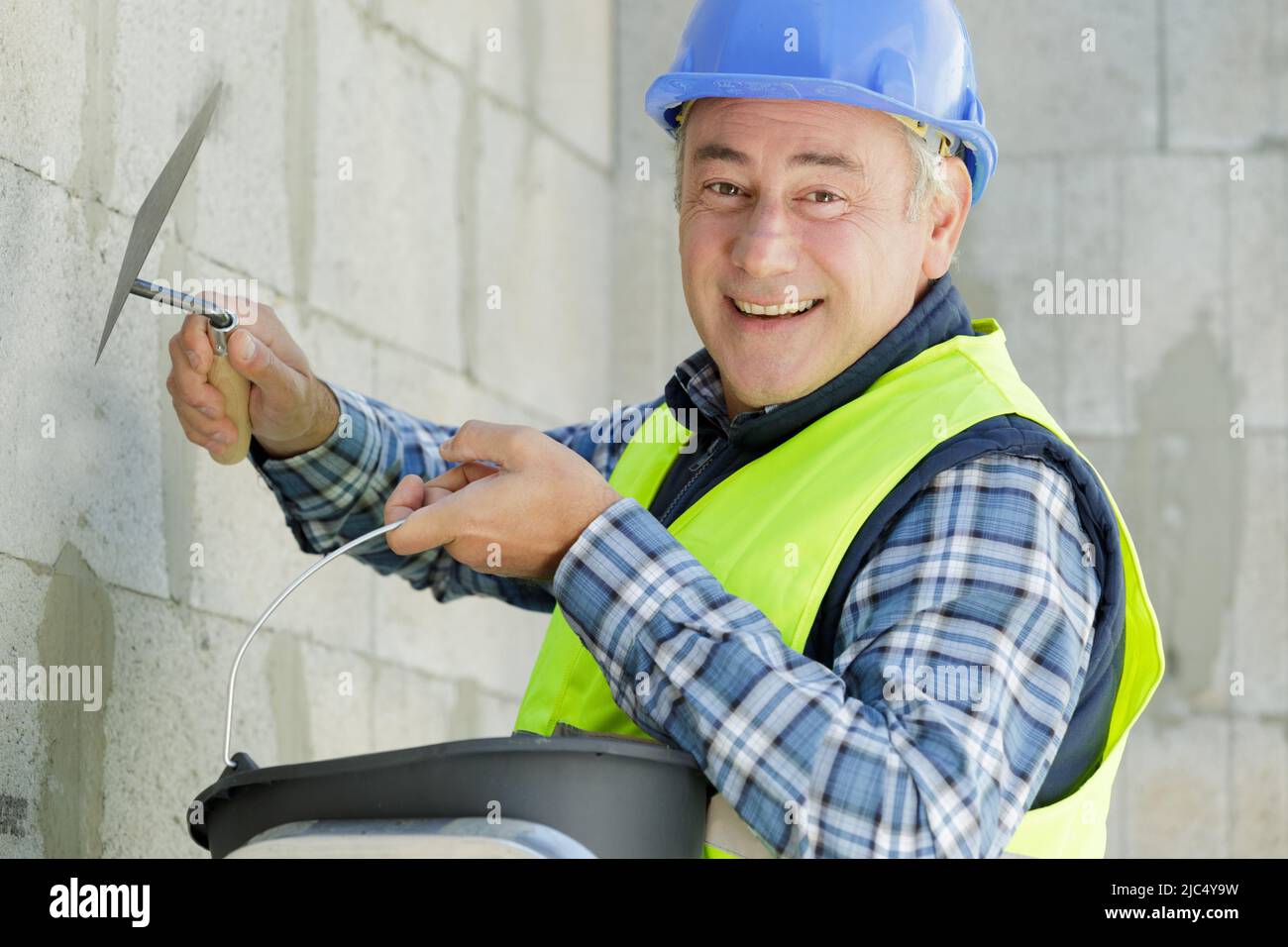 Lavoratore edile con lunga cazzuola intonacatura di una parete Foto Stock
