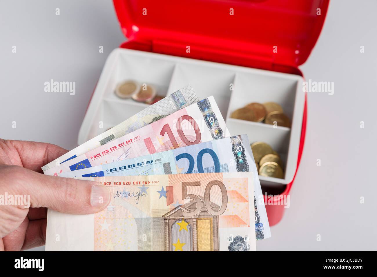 una cassa piena di soldi e un giornale di cassa Foto Stock