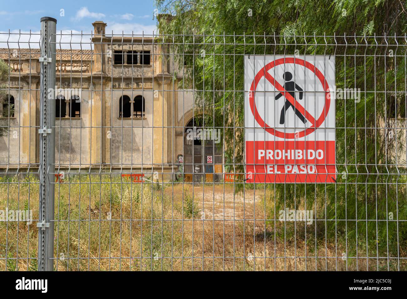 Primo piano di un segno di non trasgressione con testo spagnolo. Sullo sfondo, una vecchia fabbrica in stato di abbandono. Isola di Maiorca, Spagna Foto Stock