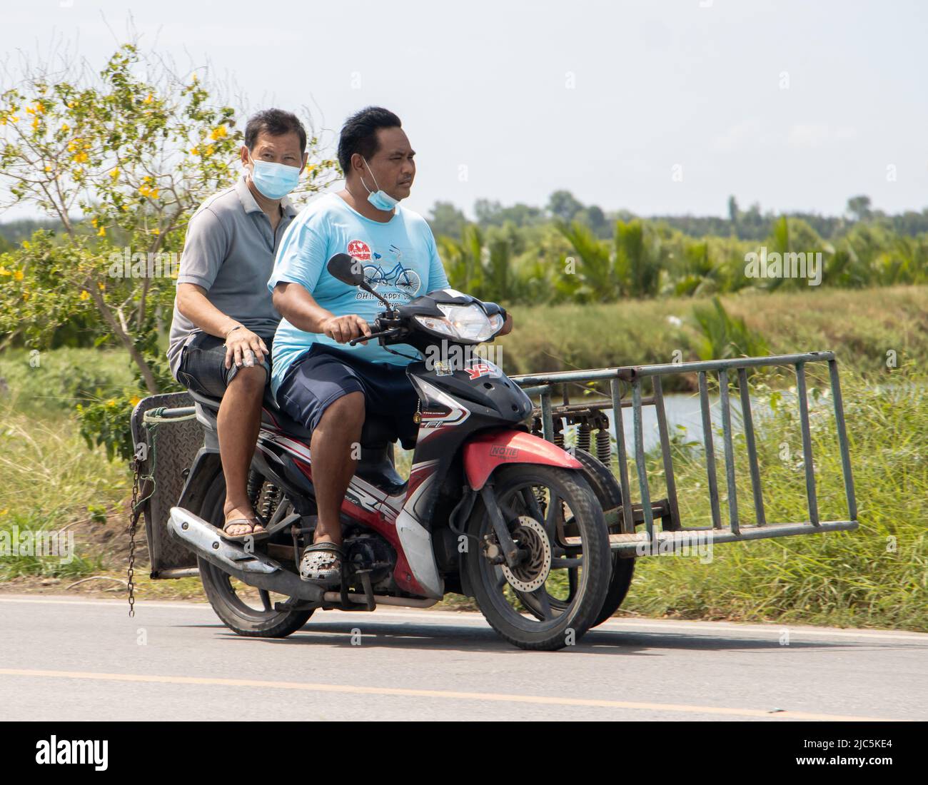 SAMUT PRAKAN, THAILANDIA, 25 2022 MAGGIO, Un uomo guida una moto a tre ruote su strada rurale Foto Stock