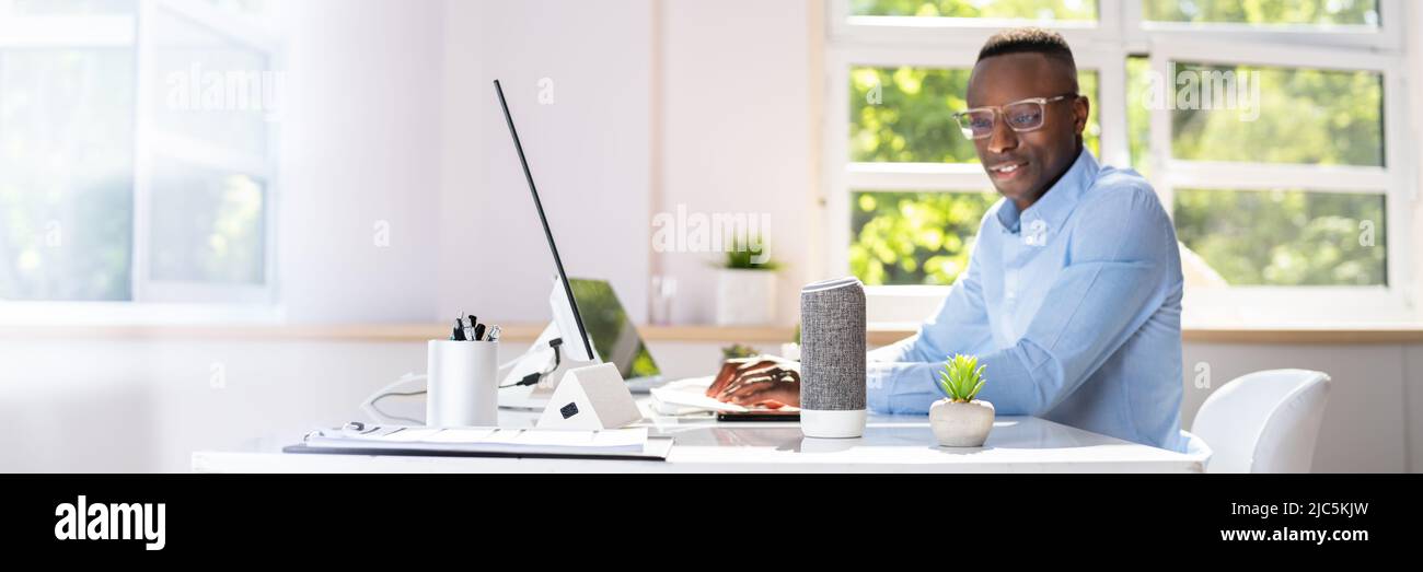 Imprenditore sorridente utilizzando Assistente vocale in ufficio Foto Stock