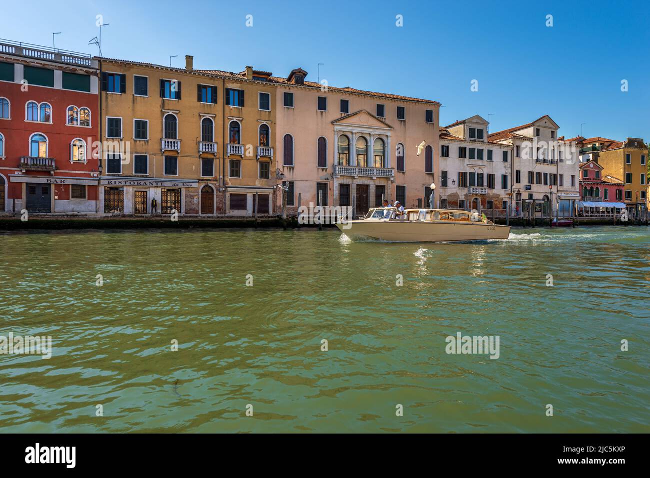 Venezia. Taxi acqueo in movimento nel Canal Grande, con due persone a bordo in una giornata di sole. Patrimonio dell'umanità dell'UNESCO, Veneto, Italia. Foto Stock