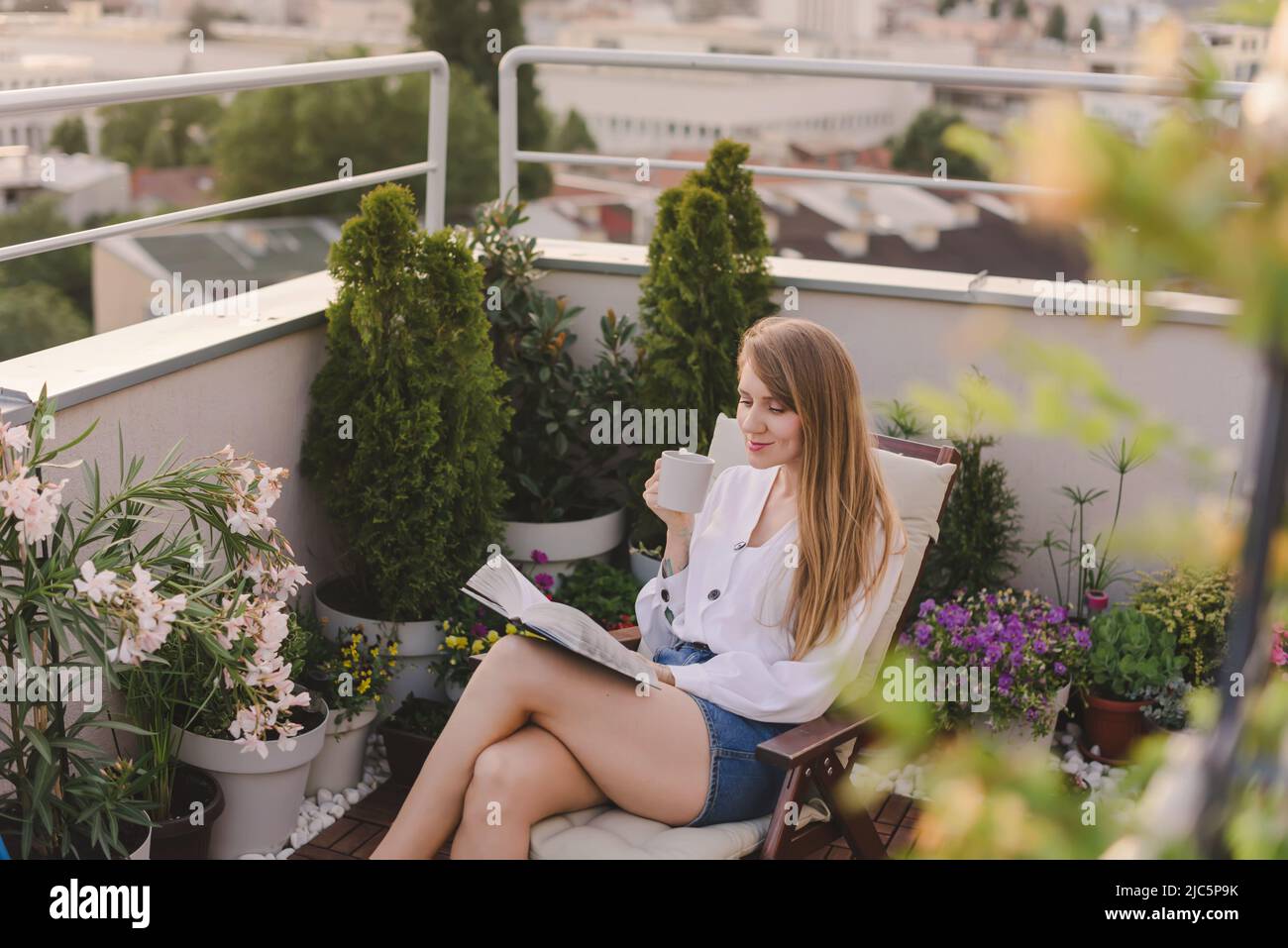 Donna con libro di lettura del caffè sul giardino sul tetto Foto Stock