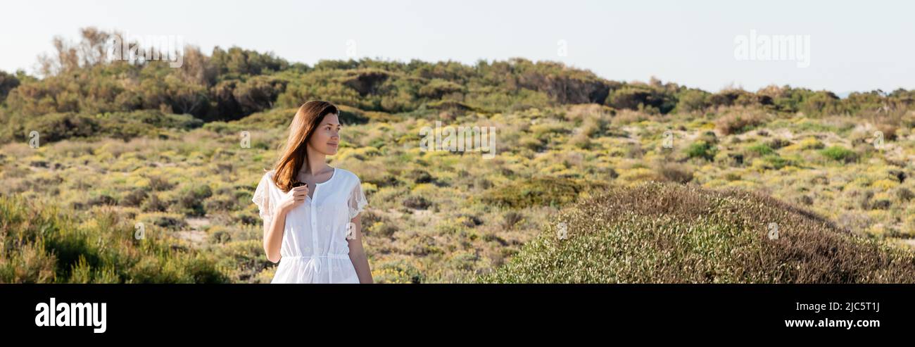 Giovane donna bruna guardando via sulla spiaggia erbosa, banner Foto Stock