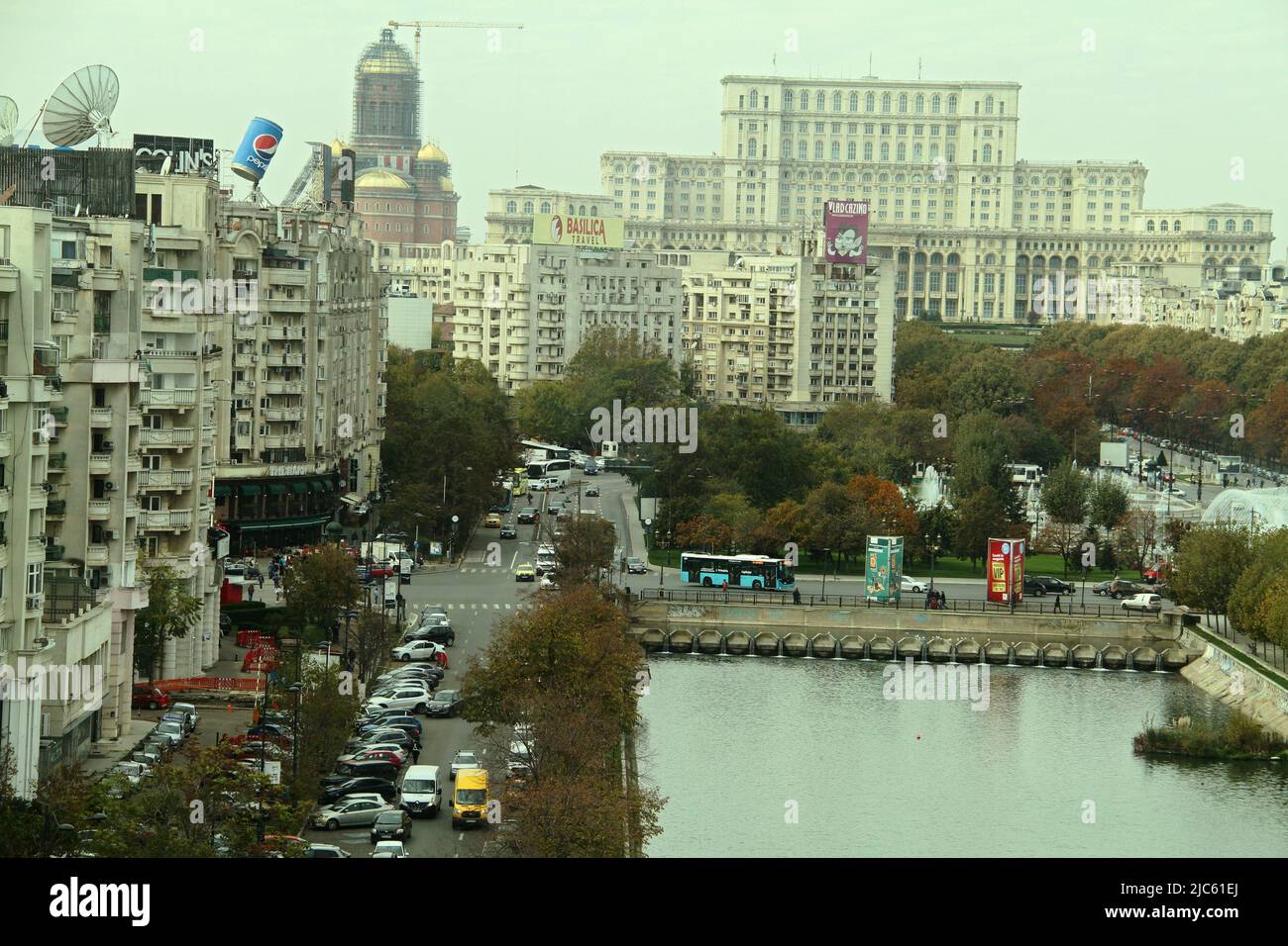 Bucarest, Romania. Il fiume Dambovita attraversa Unirii Plaza. Il Palazzo del Parlamento visto nella parte posteriore. La Cattedrale Nazionale in funzione. Foto Stock