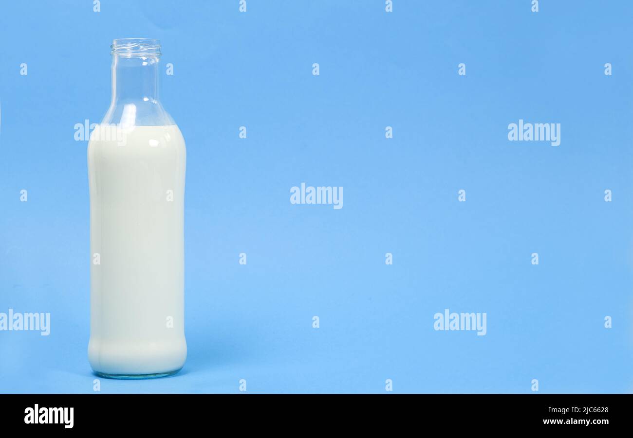 Una bottiglia di vetro di latte su sfondo blu con spazio per il testo. Foto Stock