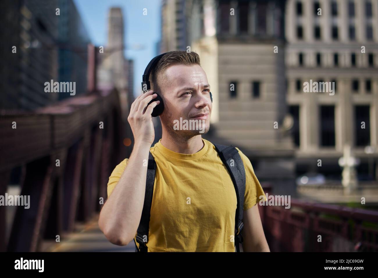 Ritratto dell'uomo mentre ascolti la musica con le cuffie wireless durante la passeggiata in città. Foto Stock