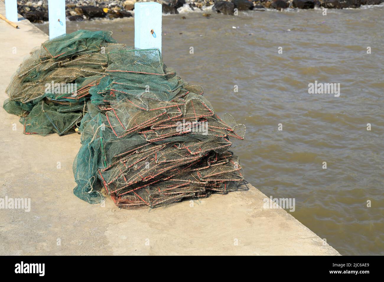 Mucchio di rete pieghevole per la cattura di gamberi e granchi sul pavimento del molo contro il mare. Vecchio granchio trappola o catcher scatole per un granchio catcher sul calcestruzzo Foto Stock