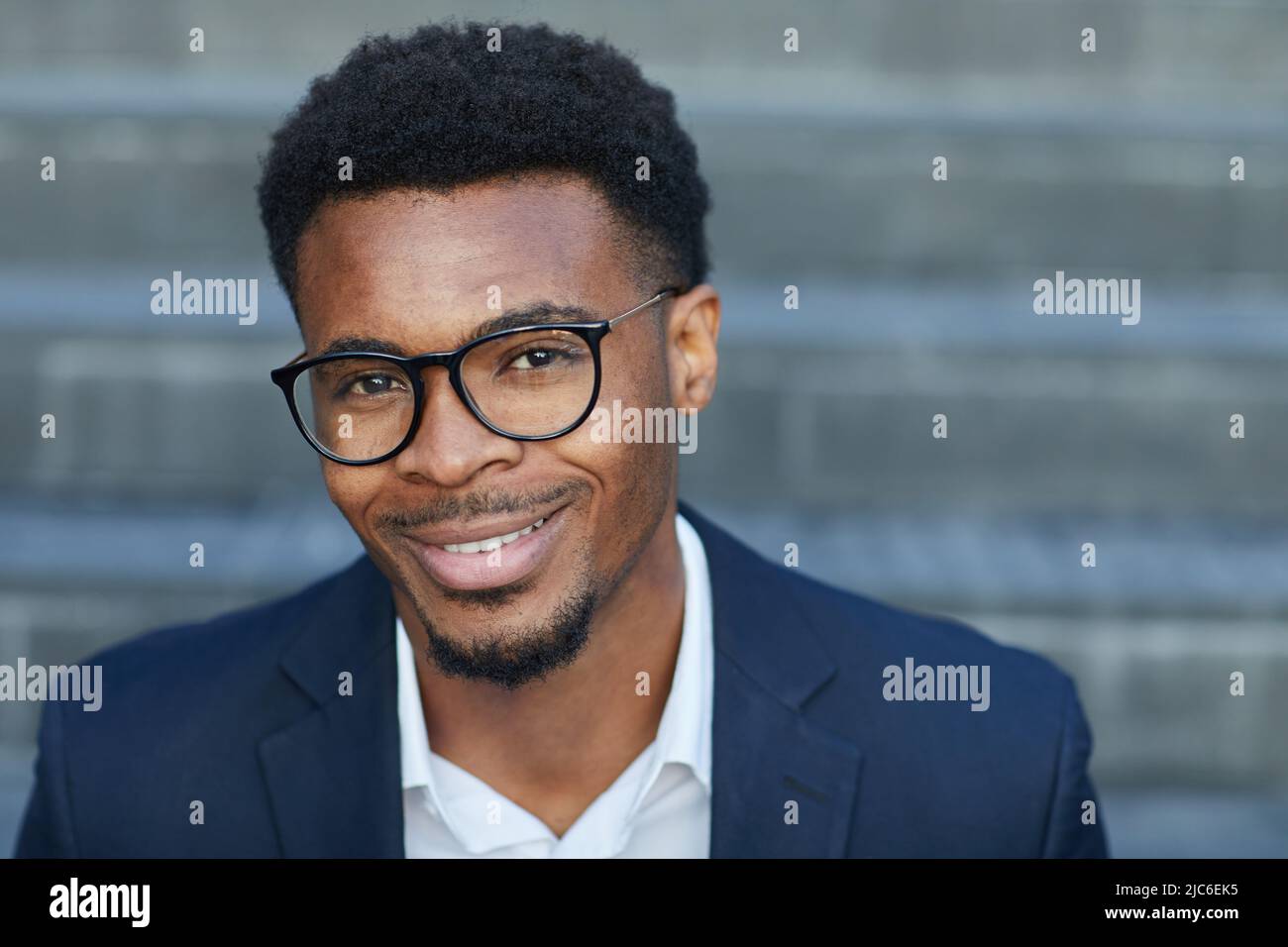 Headshot di bel giovane manager nero maschile con barba sorridente alla fotocamera all'aperto Foto Stock