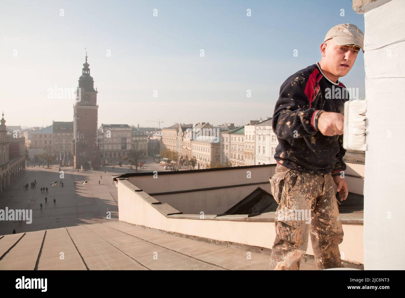 Nov 9, 2011. Polonia, Cracovia. L'operaio dipinge un camino nell'edificio storico della Piazza del mercato principale. La Torre del Municipio (a sinistra) è visibile alla Th Foto Stock