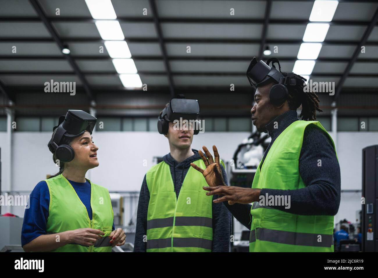 Team di ingegneri che hanno esperienza di simulazione con occhiali futuristici per realtà virtuale all'interno di una fabbrica robotica - Tech Industry e Metaverse Concept Foto Stock