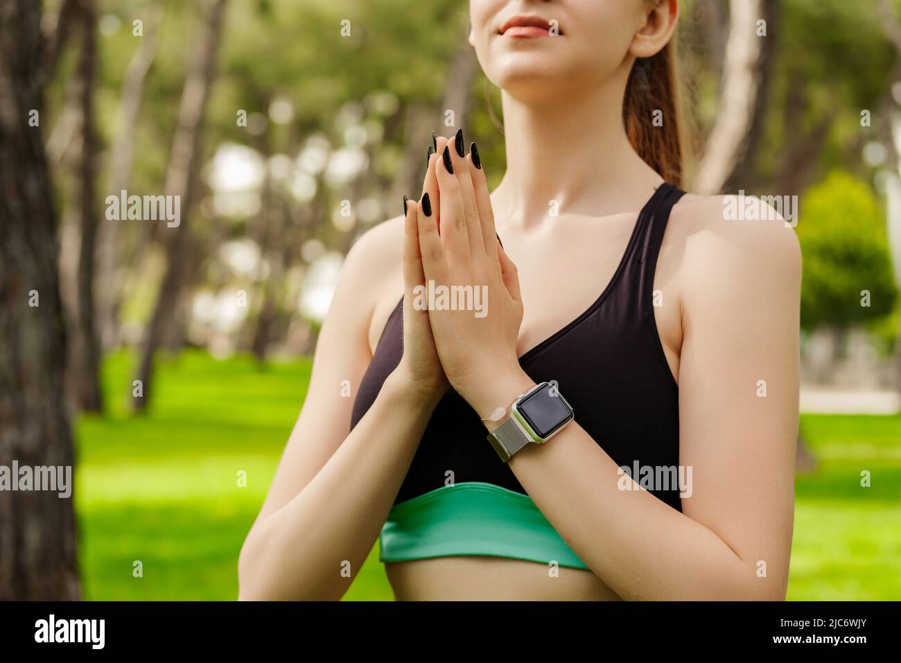 Vista ritagliata di giovane donna bruna indossando abiti sportivi sul parco cittadino, all'aperto tenere le mani in preghiera sentire superstizioso religioso. Dio. Fede, essere Foto Stock