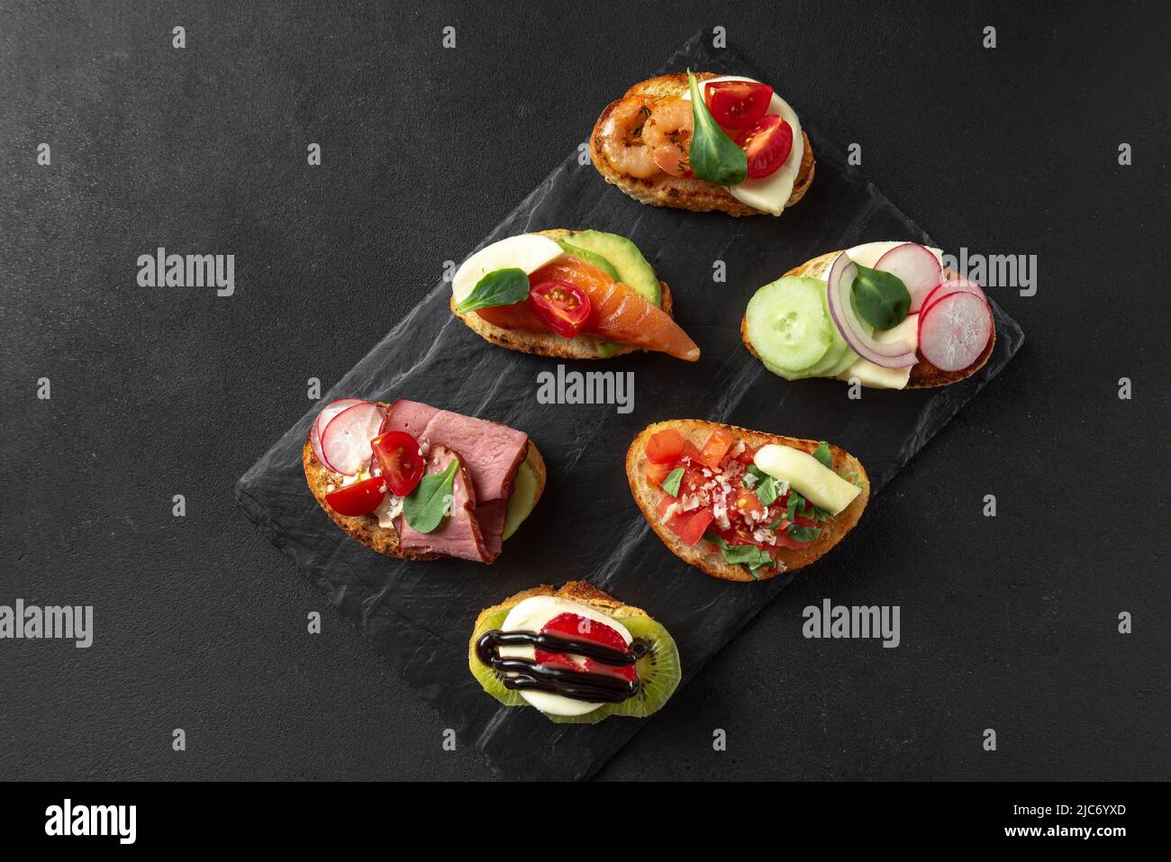 Bruschetta antipasto italiano, tradizionalmente servito prima dei piatti principali. Antipasto italiano su sfondo scuro. Brushetta Foto Stock