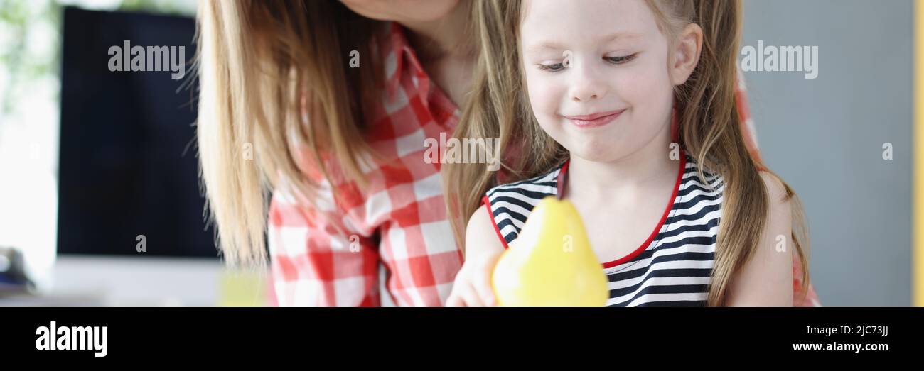 Mamma e bambino che giocano con frutta di plastica finta in cucina Foto Stock