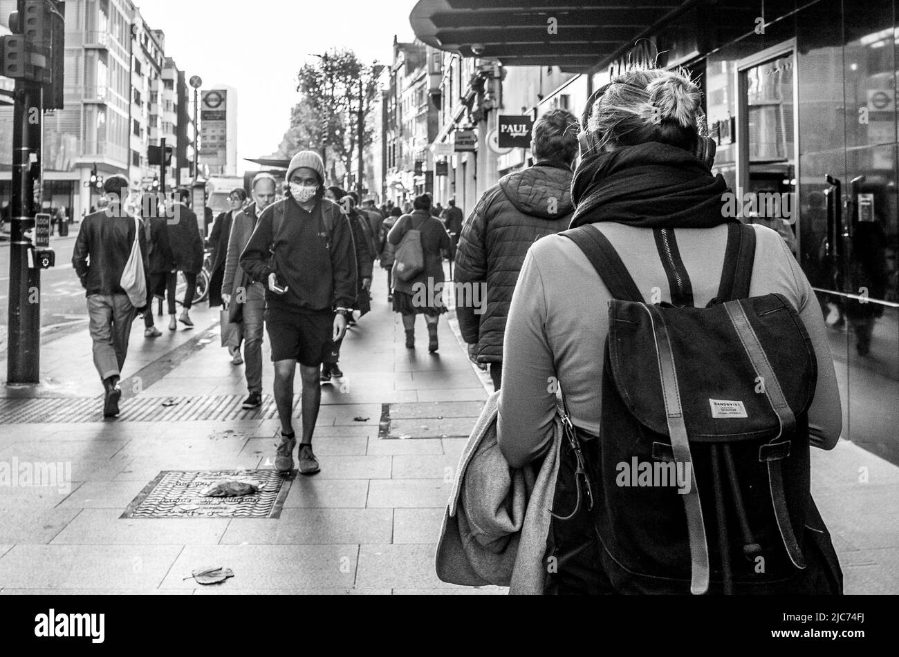 Pendolari che camminano lungo Tottenham Court Road a Londra durante l'ora di punta del mattino - Fotografia di strada in bianco e nero. Foto Stock