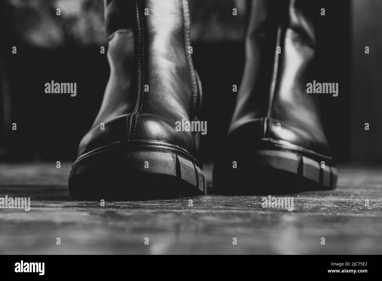 ragazza in alti stivali neri sul vecchio pavimento sporco a casa, scarpe da donna, piedi in scarpe sul pavimento, scarpe sul pavimento in legno Foto Stock