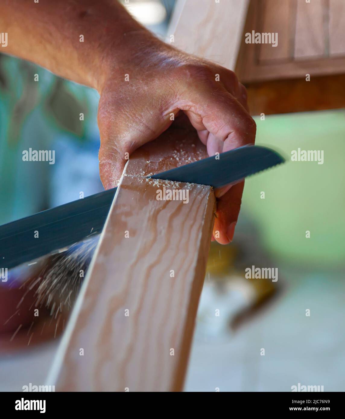 Le mani del carpentiere - tagliando la tavola di legno con la sega. Primo piano e verticale. Foto Stock