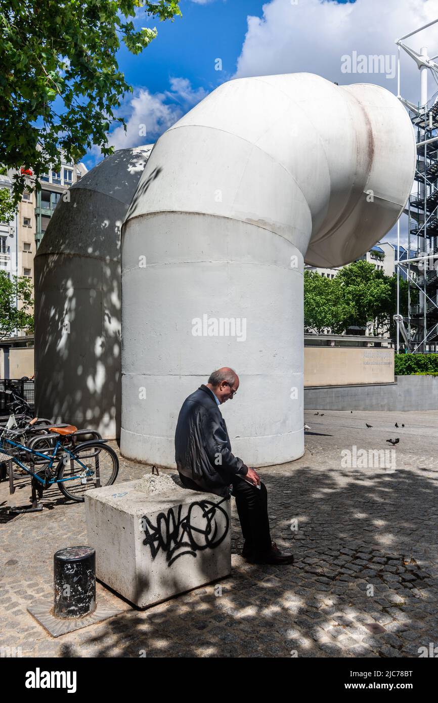 Uomo rilassante su un isolato contro una presa d'aria in Place Georges Pompidou, Parigi 4, Francia. Foto Stock