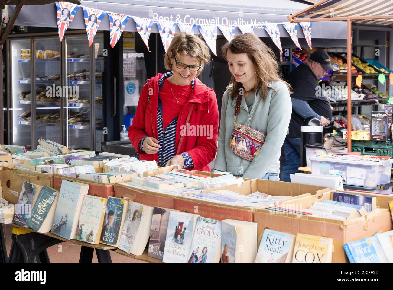 Market UK; second hand book stall UK; due donne che acquistano libri di seconda mano in una bancarella di mercato, Ely Market, Ely Cambridgeshire UK Foto Stock