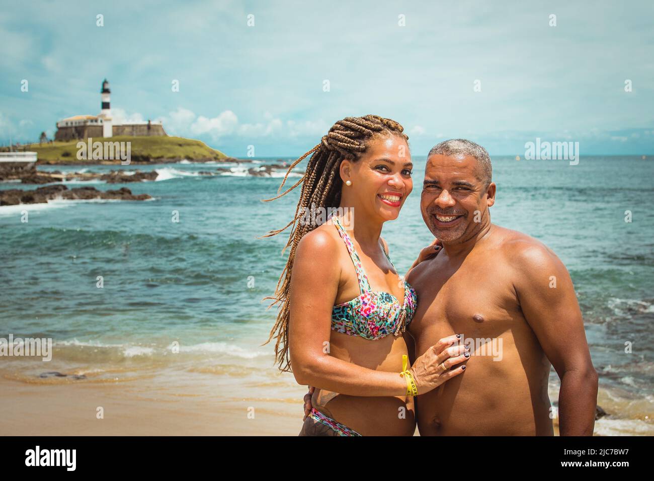 Felice brasiliano trascorrere una giornata in spiaggia nel quartiere barra, con il faro barra sullo sfondo a Salvador de Bahia, Brasile. Foto Stock