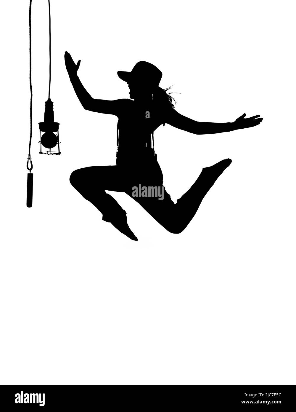 Una ballerina femminile è visto ballare sul palco. Vestita con abiti da uomo e con un cappello da uomo, si vede saltare a mezz'aria come una silhouette. Foto Stock