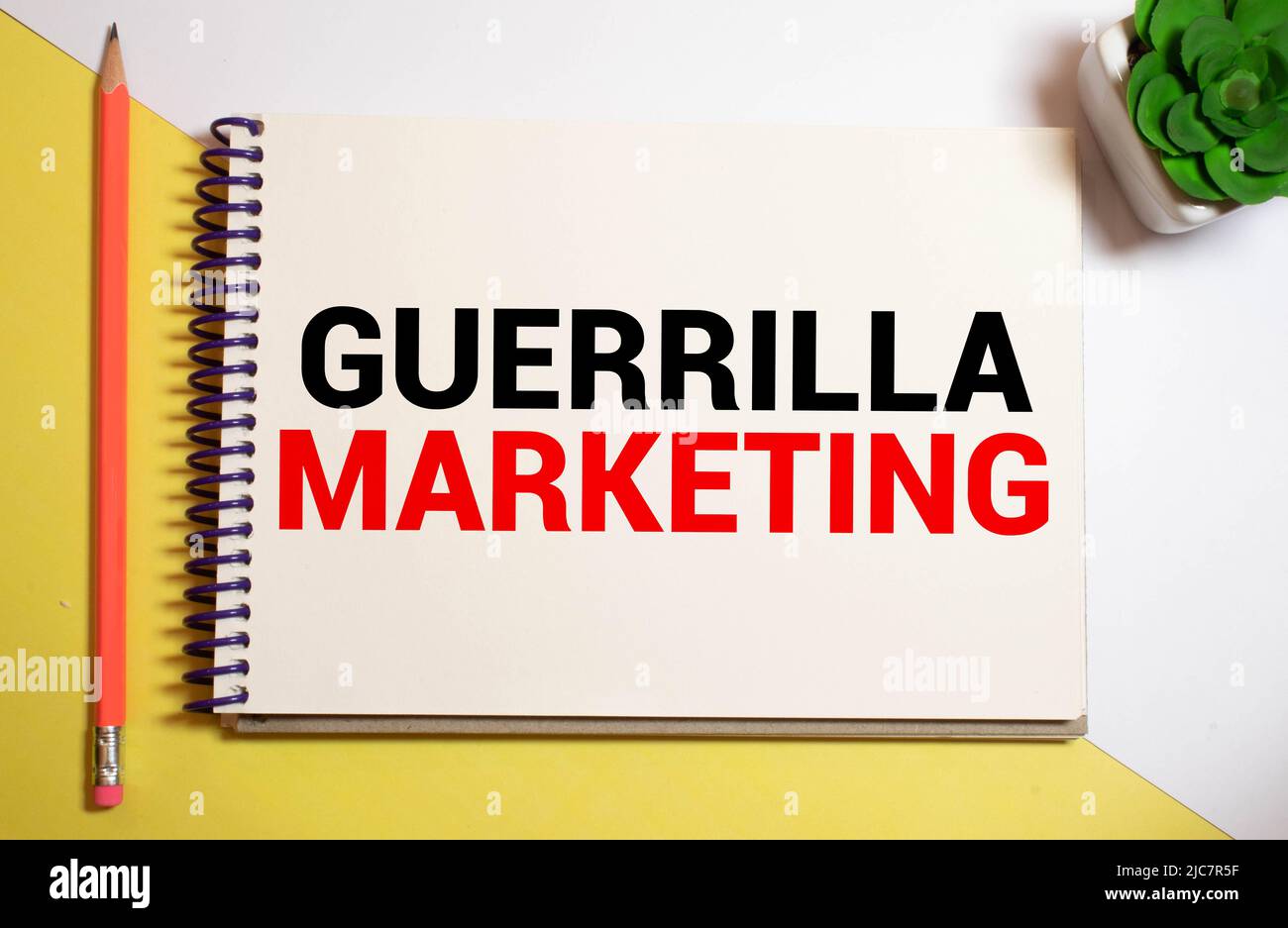 Segno di testo che mostra il marketing di guerilla. Il testo è scritto su una piccola lavagna di legno. Il libro, penna, sfondo di legno sono sulla foto. Foto Stock