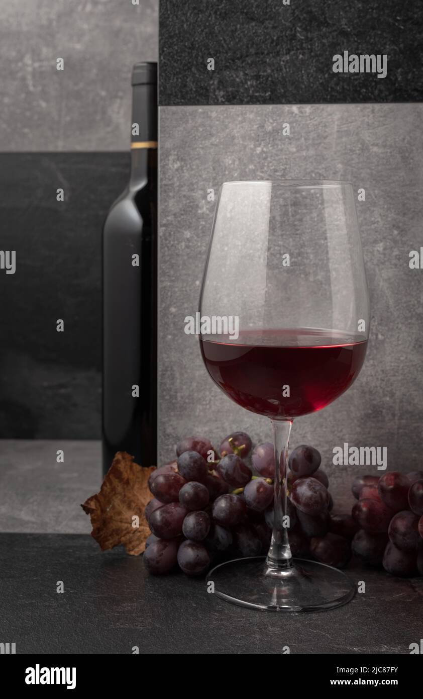 Vino rosso con uve e foglie di vite secche. Spazio di copia. Foto Stock