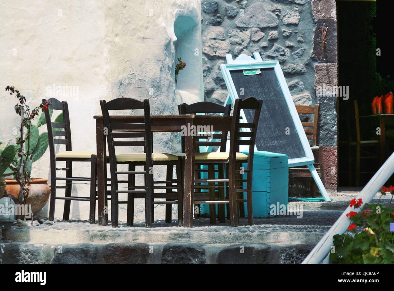 Santorini: Una taverna nella città incontaminata di Megalochori ha un piccolo ristorante all'aperto con un tavolo e sedie tradizionali in vimini Foto Stock