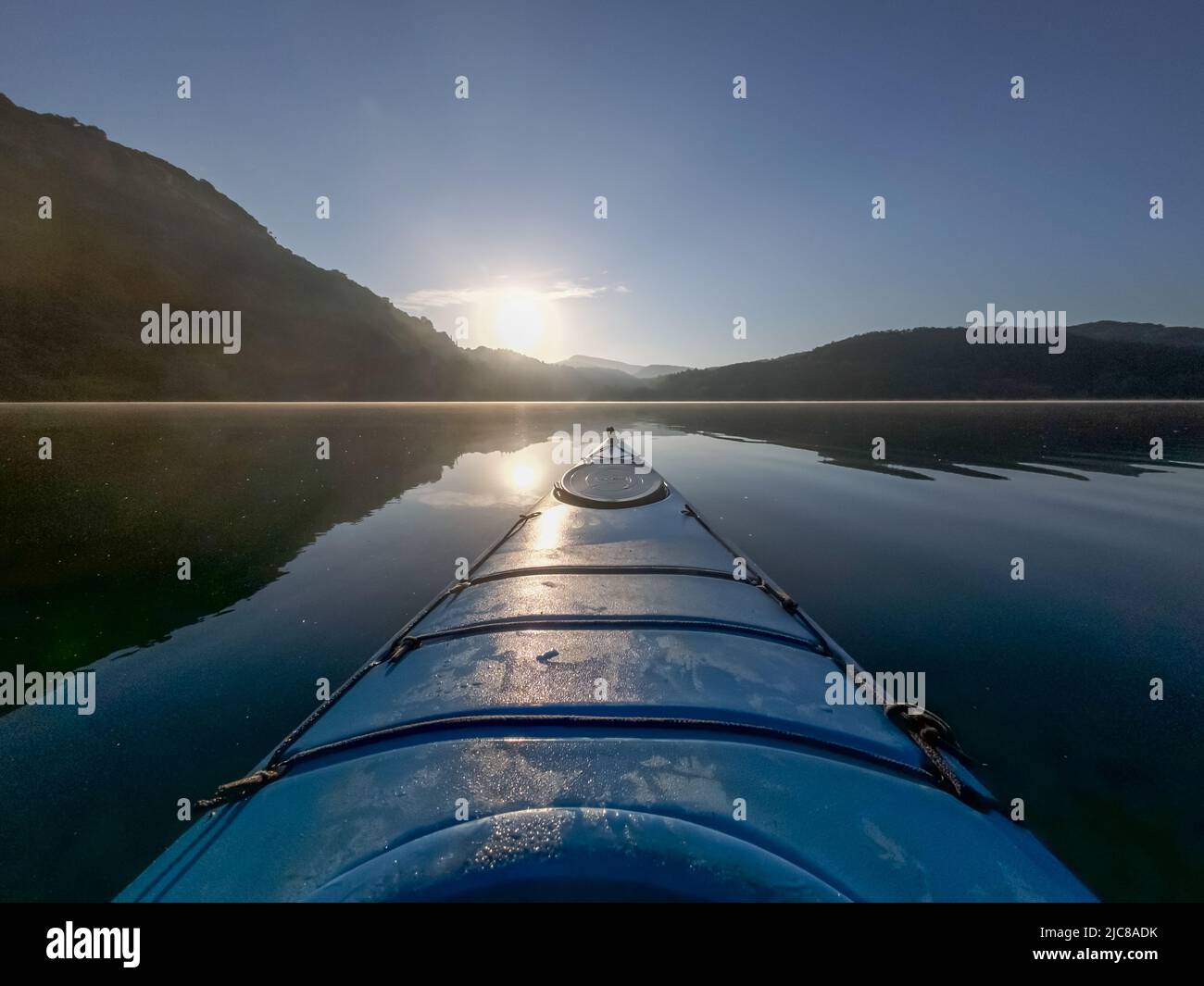 Kayak sul lago Zirou in Grecia nelle prime ore del mattino con luce solare dorata e nebbia mattutina Foto Stock