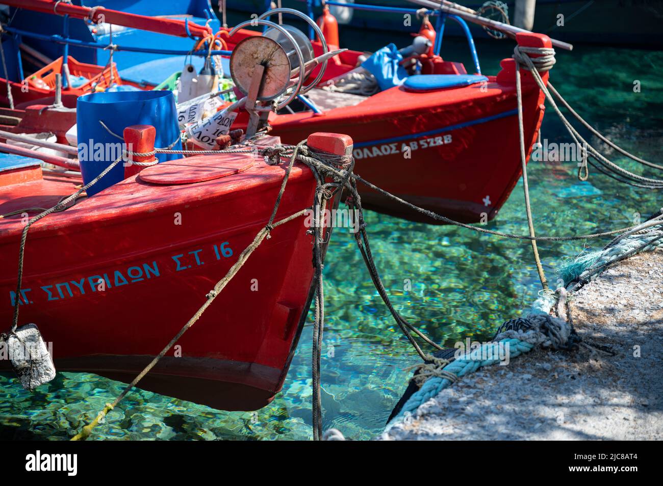 Barche da pesca rosse in acque cristalline nel villaggio di pescatori greco Trikeri sulla penisola di Pelion Foto Stock
