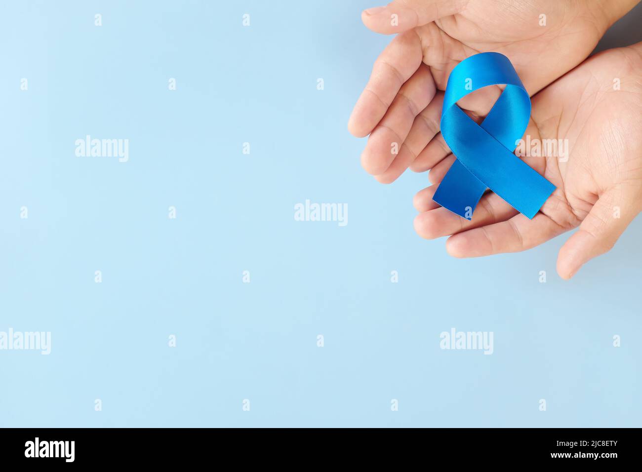 Vista dall'alto delle mani che tengono il nastro di consapevolezza blu. Cancro della prostata, cancro del colon e del colon, pace, alopecia e concetto di cura dell'artrite. Foto Stock