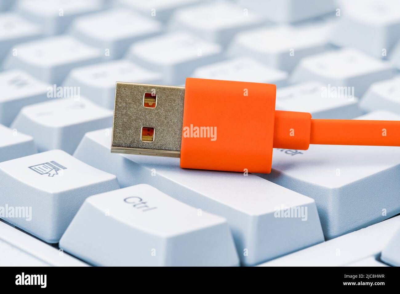 Tastiera per computer con tasti grandi e cavo USB arancione per la ricarica di periferiche o il trasferimento di dati Foto Stock