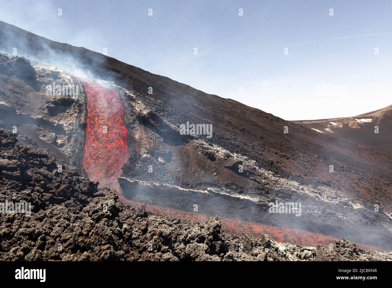 Etna Colata di lava incandescente che scorre sul vulcano di Sicilia nella Valle del Bove con fumo e canale di scorrimento lavico Foto Stock
