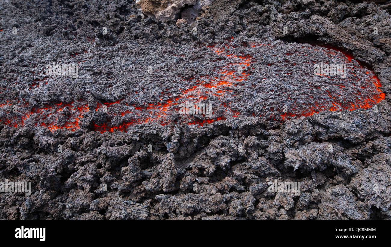 Flusso di lava incandescente sul vulcano Etna in Sicilia nella Valle del Bove con canale di fumo e flusso di lava Foto Stock