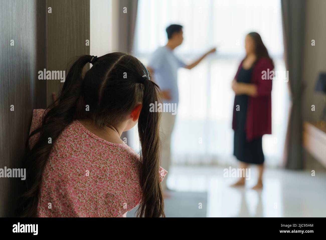 La violenza familiare e il concetto di conflitto familiare, triste bambina con sfocatura di madre che combatte padre con litigio a casa. Foto Stock