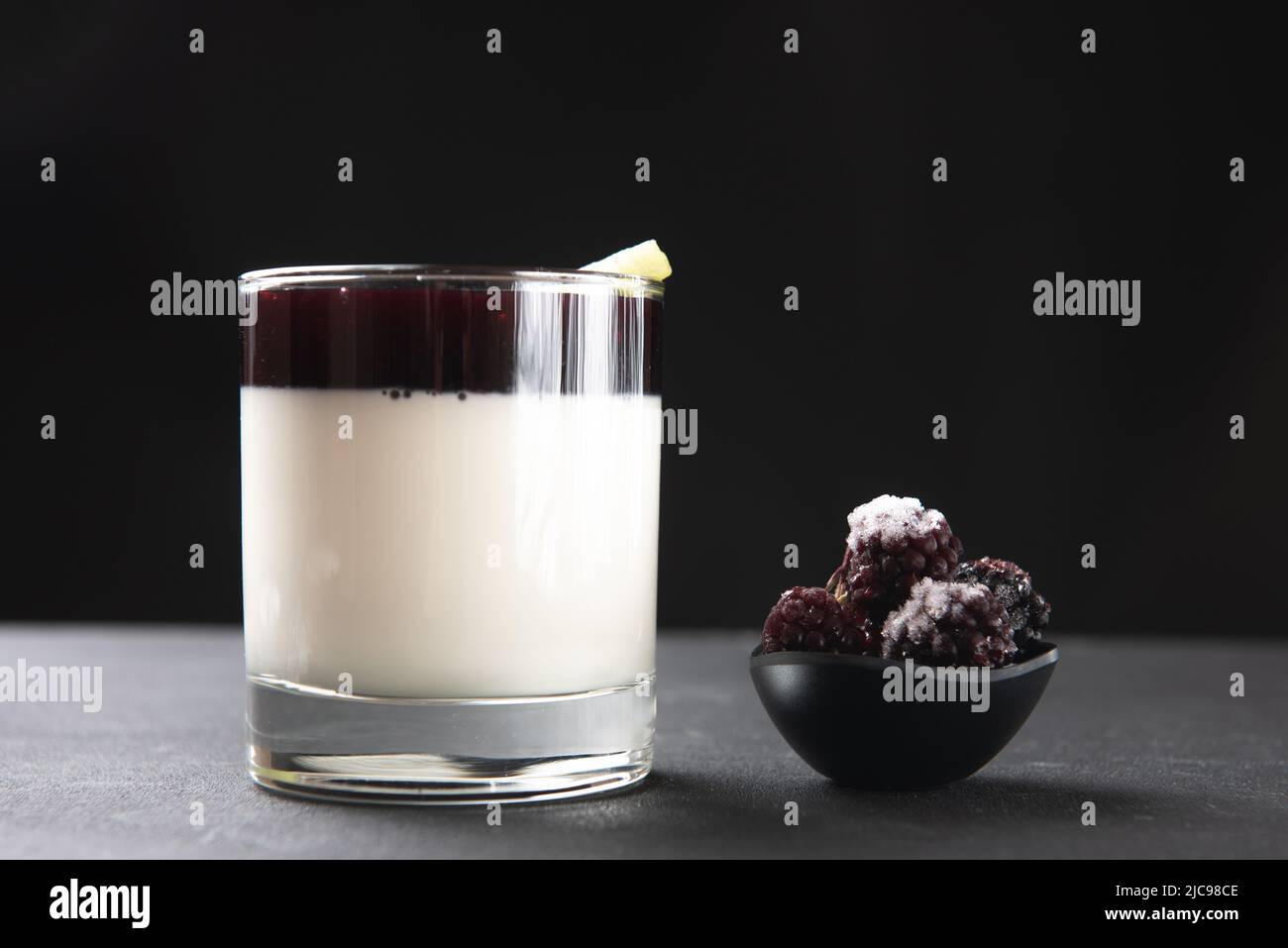 bicchiere con dessert pana cotta su sfondo nero con frutti di bosco Foto Stock